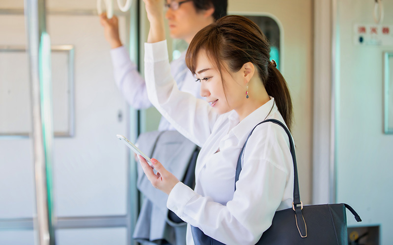 通勤電車でスマホを使って勉強する女性